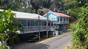 A two-story building with a red roof and blue exterior walls, featuring a balcony and a staircase leading to the upper floor. - Near the beach family (West End)