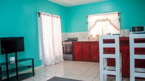 A kitchen with teal walls, a microwave, and a stove. - Near the beach family (West End)