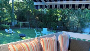 A wicker sofa with striped cushions on an outdoor deck. - Cozy Hamptons Escape 3BR Minutes From Beach! (Hampton Bays)