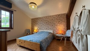 Ein Schlafzimmer mit einem hölzernen Bett, einer Steinwand, einer Pendelleuchte und einem Fenster.