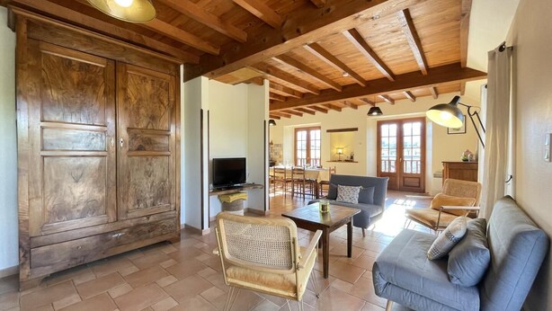 Amplia sala de estar con techo de madera, un armario grande, un sofá, una mesa de comedor y un televisor.