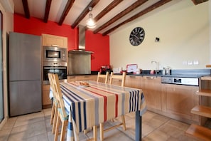 Een moderne keuken met een eettafel, houten keukenkastjes en een rode accentmuur.