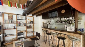 A bar area with a brick wall, bar stools, a coffee machine, and a bookshelf with books.