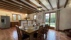 A spacious kitchen with a large dining table, wooden cabinets, and a built-in refrigerator. - Aikobeko - Sare - Gîte (SARE)