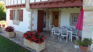 A stone building with a balcony, a table and chairs, and potted plants. - Aikobeko - Sare - Gîte (SARE)