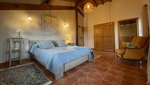 A bedroom with a bed, bedside lamps, a chair, a wardrobe, and a hanging light fixture. - Aikobeko - Sare - Gîte (SARE)