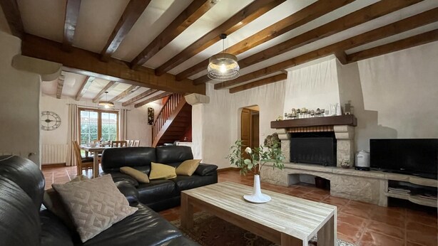 A spacious living room with a black leather sofa, a wooden coffee table, and a fireplace. - Aikobeko - Sare - Gîte (SARE)