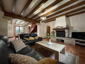 A spacious living room with a black leather sofa, a wooden coffee table, and a fireplace. - Aikobeko - Sare - Gîte (SARE)