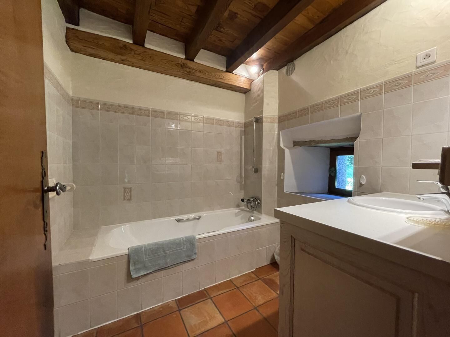 A bathroom with a bathtub, a sink, and a window.