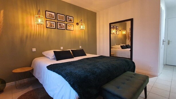 Een slaapkamer met een bed, nachtkastjes, een spiegel en wandlampen.