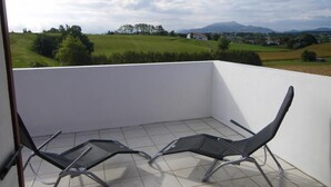 A balcony with two chairs and a view of a green field and mountains. - Xokobia - Arbonne - Gîte (ARBONNE)