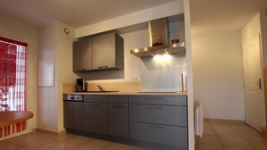A modern kitchen with grey cabinets, a stainless steel range hood, and a wooden countertop. - Xokobia - Arbonne - Gîte (ARBONNE)