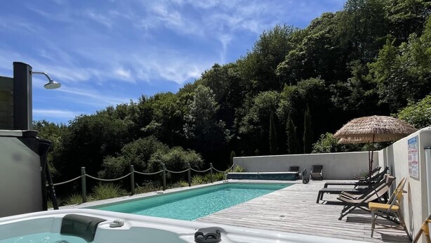 A hot tub with a wooden deck and lounge chairs, surrounded by a pool and a forested area. - PHORDOY 3 - BARCUS - Gîte (BARCUS)