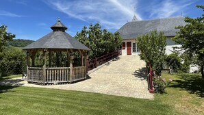 A gazebo with a tiled roof, a red fence, and a building with a red door and a grey roof. - PHORDOY 3 - BARCUS - Gîte (BARCUS)