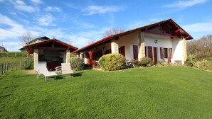 Ein zweistöckiges Haus mit überdachter Terrasse und gepflegtem Rasen.