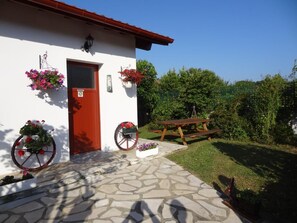 Guests can enjoy a charming entrance with a stone-paved patio and a picnic table on the lawn.