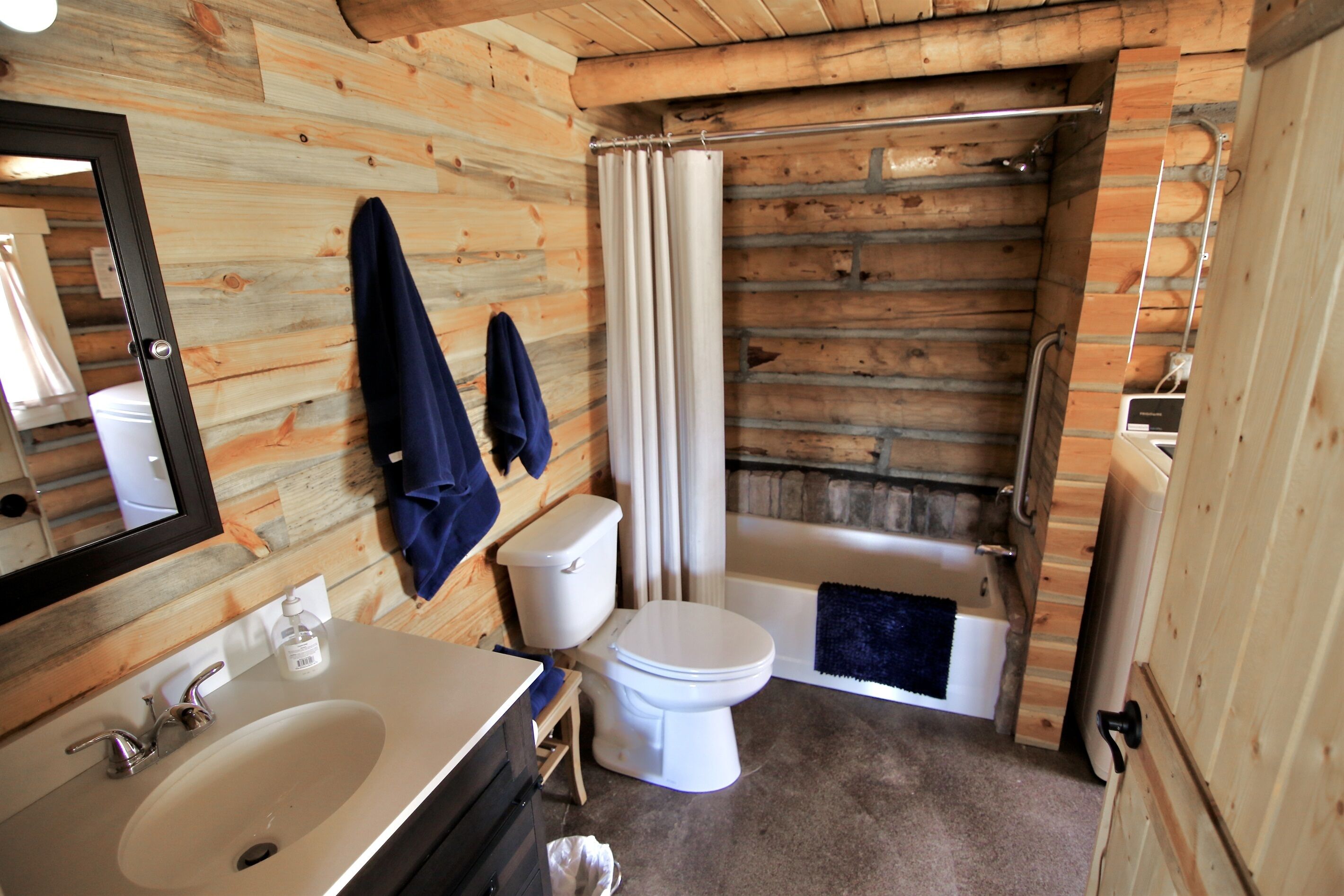 Een badkamer met een houten inrichting, een wit wastafelmeubel, toilet en een bad.