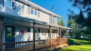 A two-story house with a covered porch and a satellite dish. - Coby’s Cove - Four Season Cottage Huntsville Muskoka Waterfront  (Emsdale)