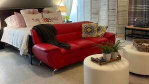 Ein modernes Wohnzimmer mit einem roten Sofa, einem weißen Hocker und einem Deckenventilator.