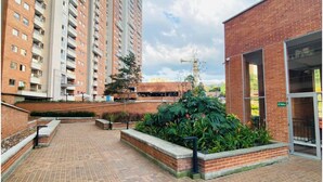 A courtyard with a brick building, a high-rise residential building, and a construction crane in the background.