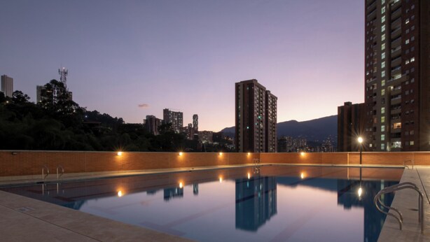 A rooftop pool with a clear view of surrounding high-rise buildings and a cityscape at dusk.