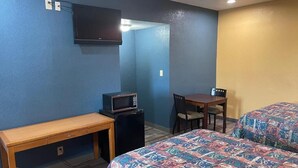 A room with a bed, a desk, a chair, a microwave, and a television. - Kenwood Court Motel (Wilson)