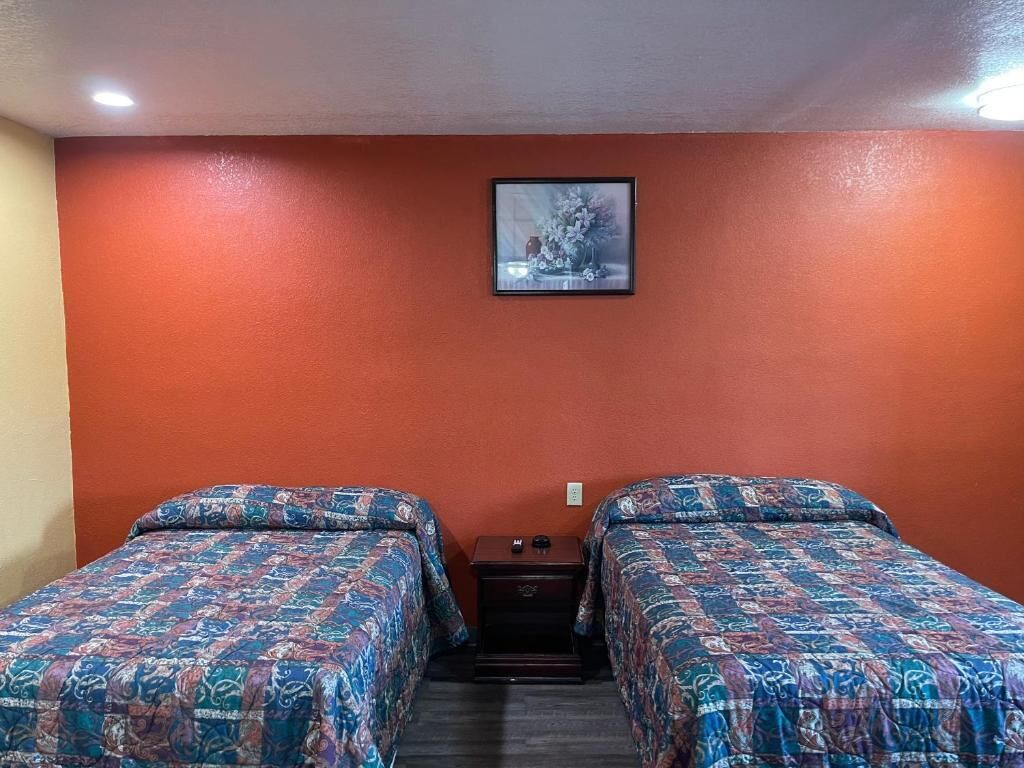 A room with two beds, a framed picture on the wall, and a small table between them.