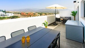 Ein Balkon mit Esstisch, Stühlen, Sonnenschirm und einer kleinen Pflanze.