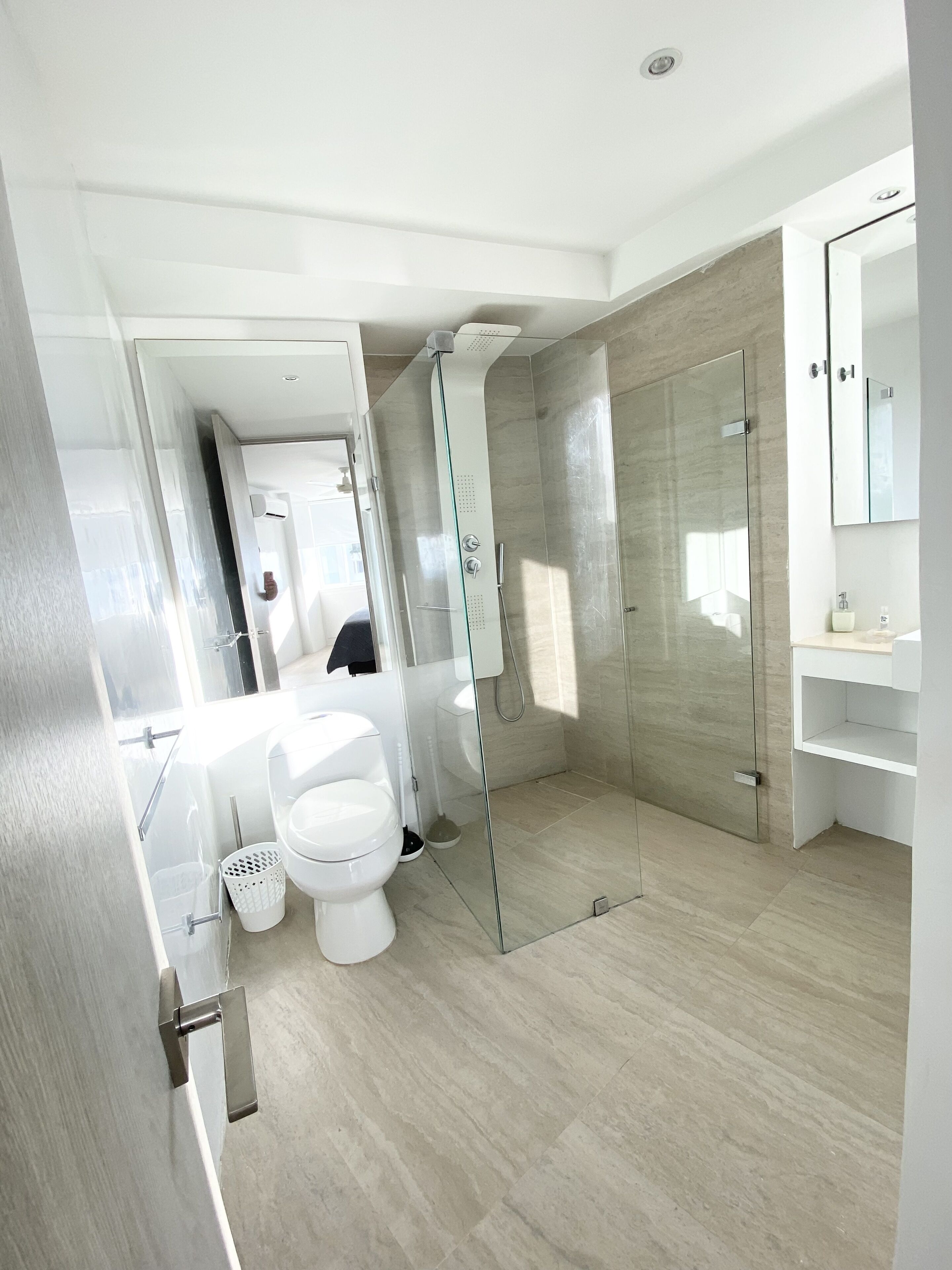 Un baño moderno con ducha envuelta en vidrio, inodoro y lavamanos.