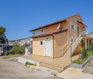 Una casa a due piani con tetto in tegole, un portone d'ingresso e una scala che conduce al piano superiore.