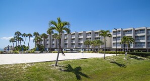 Um hotel à beira-mar com várias varandas, palmeiras e uma área de praia arenosa.