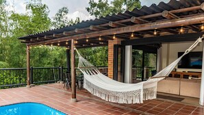 A poolside area with a hammock, outdoor seating, and a pergola with string lights. - Luxury Villa • Pool • Jacuzzi • Spa • Maid/Cook • 5 min from Panaca Park. (Quindío)