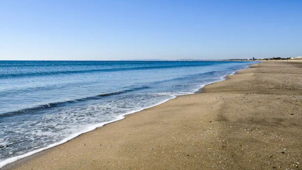 Een strand met helderblauw water en een zandstrand.
