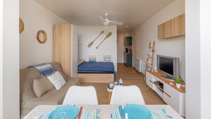 Een moderne, goed verlichte kamer met een bed, een bank, een televisie en een eethoek.