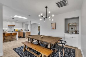 Une cuisine moderne avec une table Ă manger en bois, des chaises noires et un tapis Ă motifs noir et blanc.