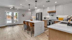 Una cocina moderna con una isla central, armarios de madera y electrodomésticos de acero inoxidable.