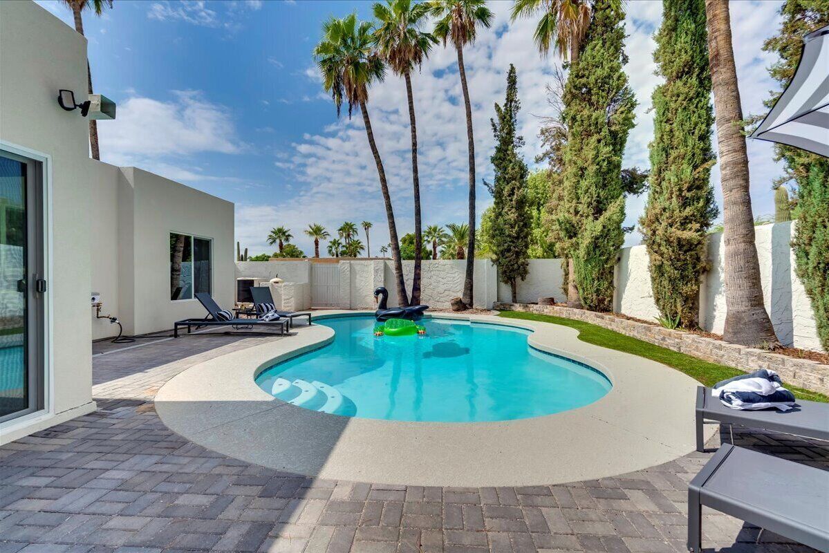 Ein moderner Pool im Freien mit Liegestühlen und Palmen.