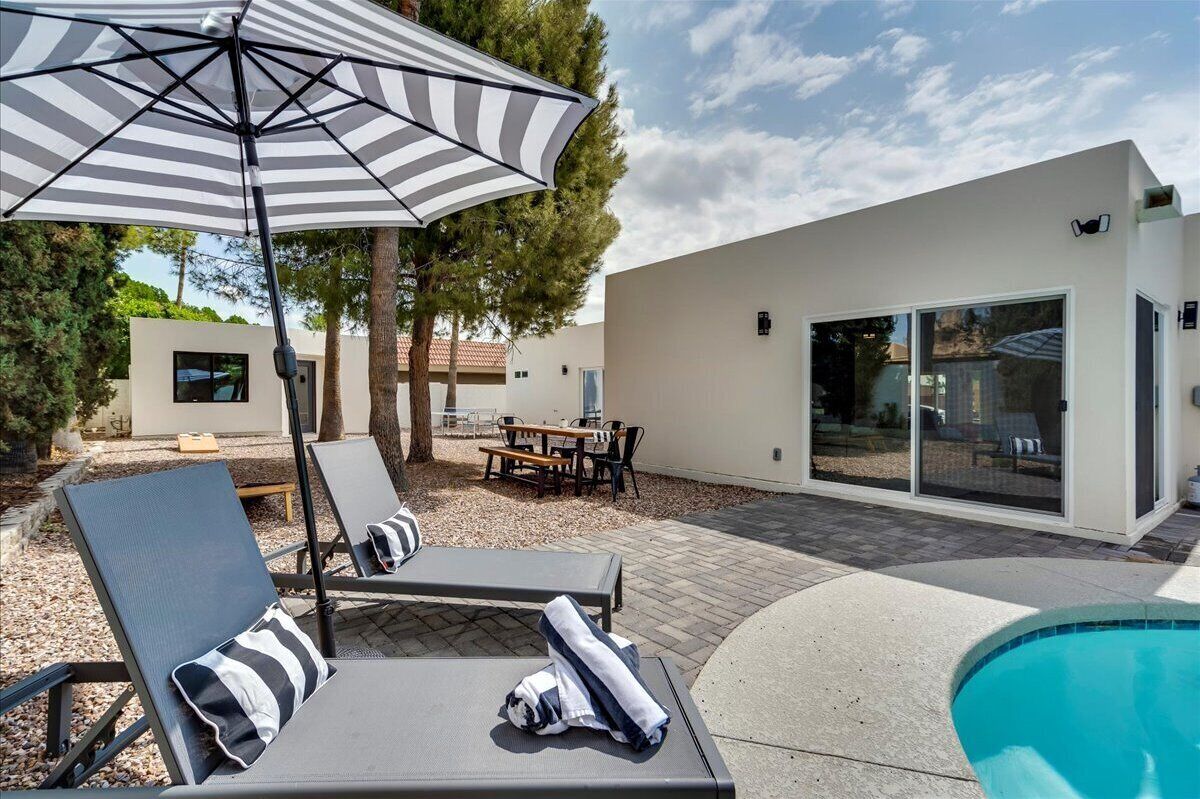 Et moderne poolområde med liggestole og en stribet parasol.