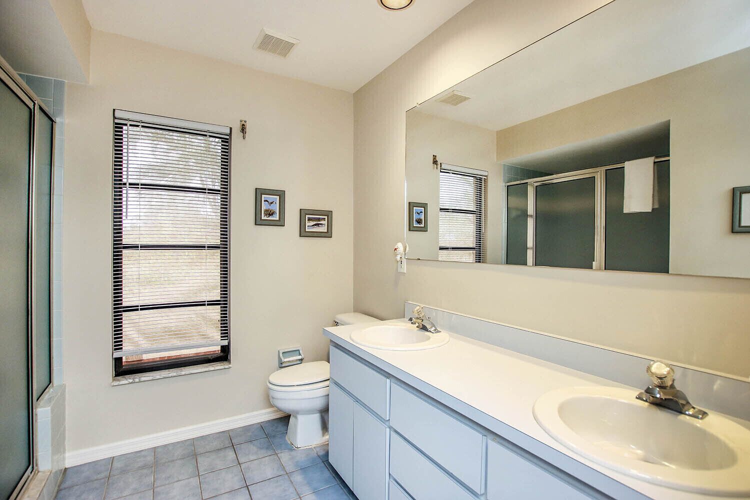 A bathroom with two sinks, a toilet, and a large mirror.