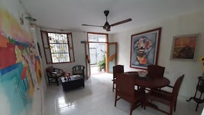 A dining area with a table and chairs, a ceiling fan, and a mural on the wall. - 3G1-1 Apartamento Ciudad Antigua Getsemani (Cartagena)