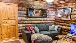 A log cabin interior with a sofa, a television, and a wooden door. - Salmikankaan kelo d2 by Interhome (Kuusamo)