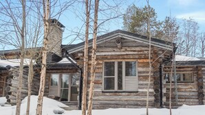 A log cabin with a chimney, large windows, and a snow-covered landscape. - Salmikankaan kelo d2 by Interhome (Kuusamo)