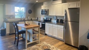Una cocina moderna con armarios blancos, electrodomésticos de acero inoxidable y una mesa de comedor de madera.