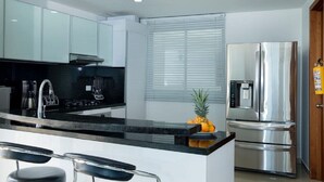 A modern kitchen with a central island, stainless steel appliances, and a window with blinds. - PH17P Penthouse Cartagena Frente al mar (Cartagena)