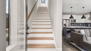 Een modern interieur met een houten trap die naar een keuken leidt.