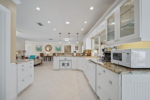 A spacious kitchen with white cabinetry, granite countertops, and a built-in microwave. - Screened-In Heated Pool and 5 min from the beach. Child friendly.  (Deerfield Beach)