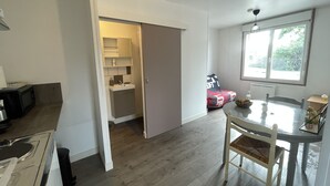 A modern kitchen with a dining area, a microwave, a sink, and a window with a view of greenery. - Studio near University and Hospital BETHUNE (Beuvry)