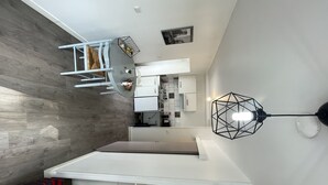A modern kitchen with white cabinets, a wooden floor, and a geometric pendant light. - Studio near University and Hospital BETHUNE (Beuvry)