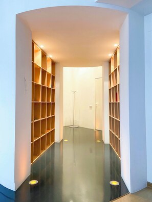 A hallway with a polished floor, wooden shelving units on both sides, and recessed lighting.