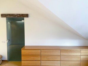 Una habitación con un armario de madera, una puerta y un techo inclinado.